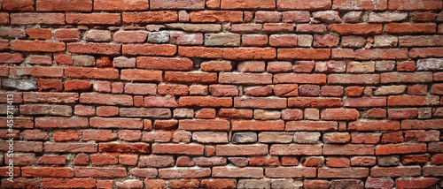Ancient brick wall of an historical building in Italy with deformation due to centuries, original irregular pattern, textured background.
