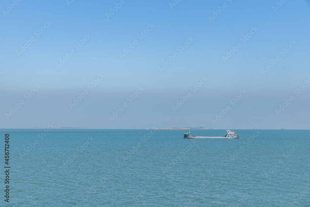 The ocean under the blue sky, the ship staying at the dock or the sea