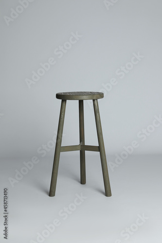 Stylish wooden stool on light grey background. Interior element