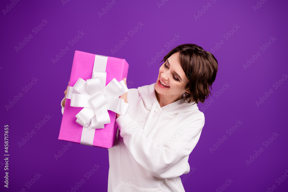 Photo of smiling positive beautiful gorgeous girl hold birthday present biggest wish isolated on violet color background Photo of smiling positive beautiful gorgeous girl hold birthday present biggest wish isolated on violet color background