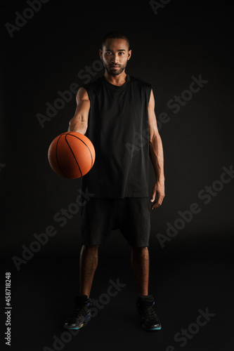 Young sportsman looking and reaching basketball at camera