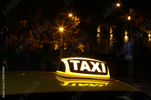Taxi car with yellow sign on city street at night