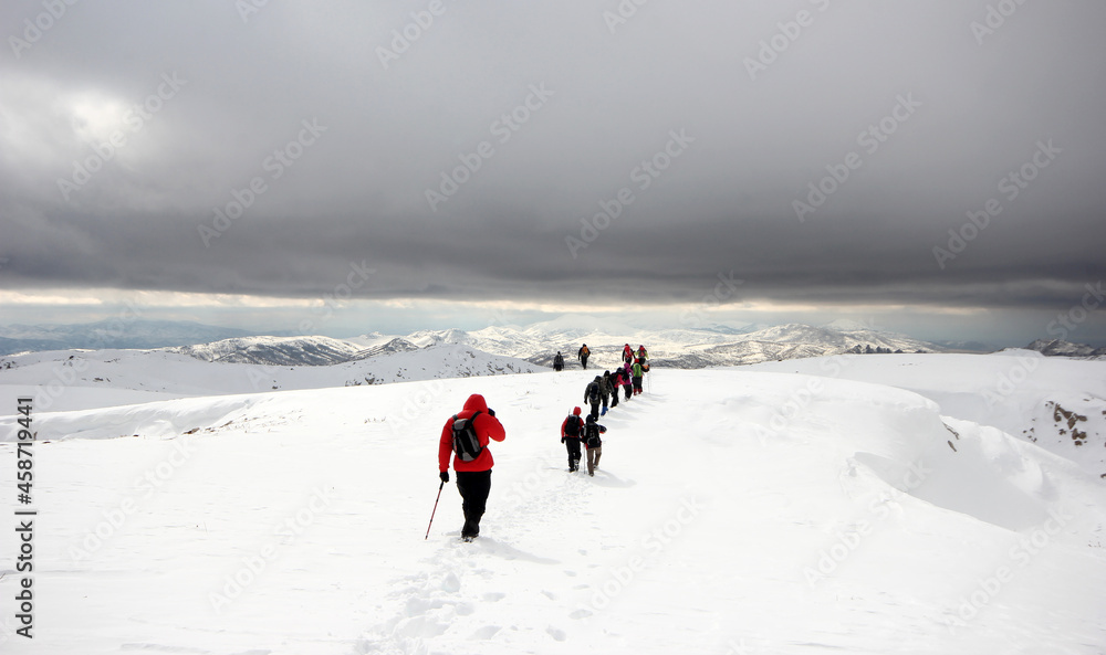 Group of mountaineers walking trough the mountains covered with snow...