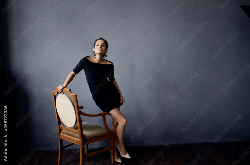 beautiful woman in a black dress near the chair luxury fashion dark background