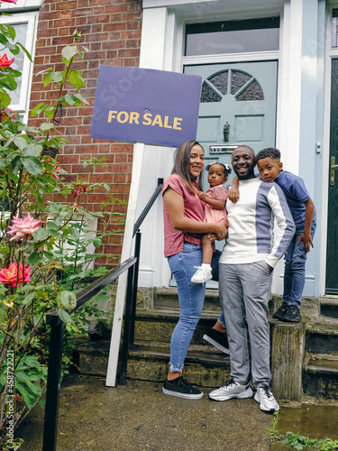 Parents with son and daughter in front of house for sale