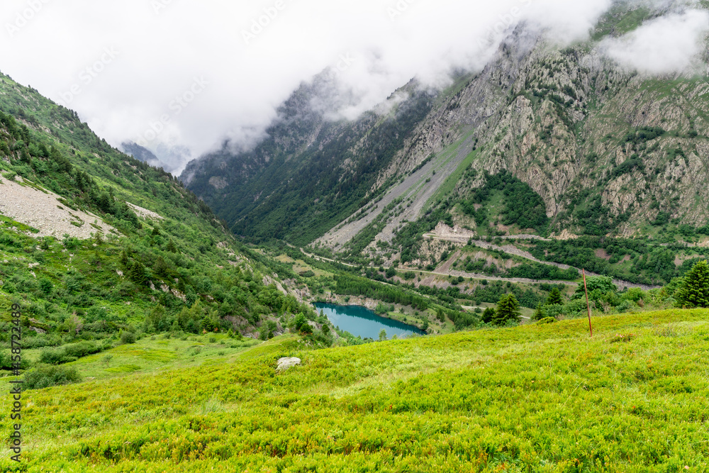 Fototapeta premium Beautiful summer panorama of the small mountain lake in Vaujany, France. Cloudy view in the French Alps, Europe. Scenery landscape of high plateau.
