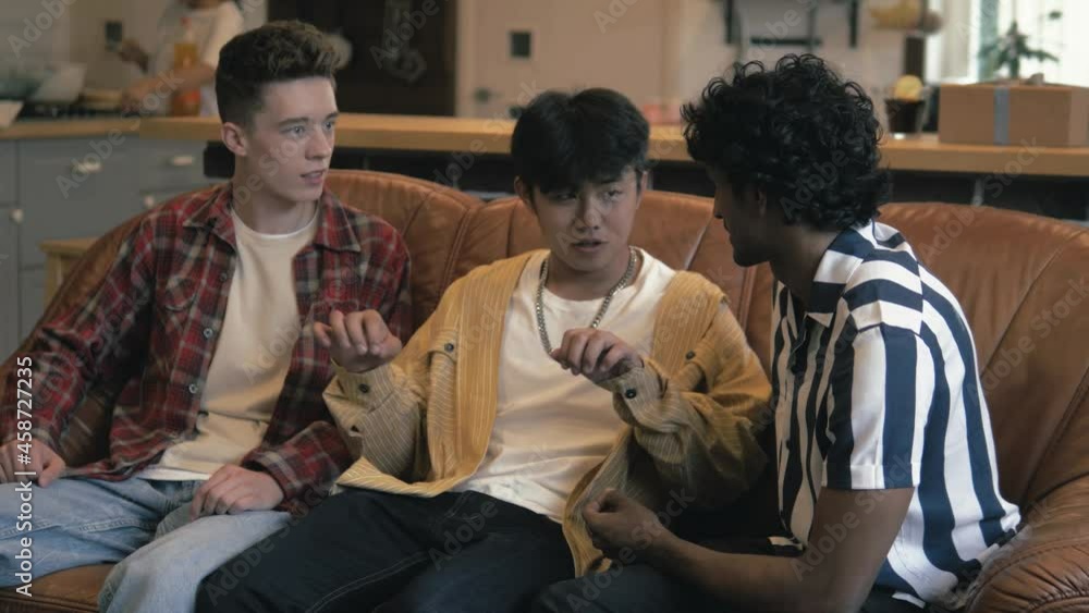 Happy positive handsome multiethnic friends laughing talking, multiracial guys having communication together at home, young multicultural students discussing having fun Happy positive handsome multiethnic friends laughing talking, multiracial guys having communication together at home, young multicultural students discussing having fun