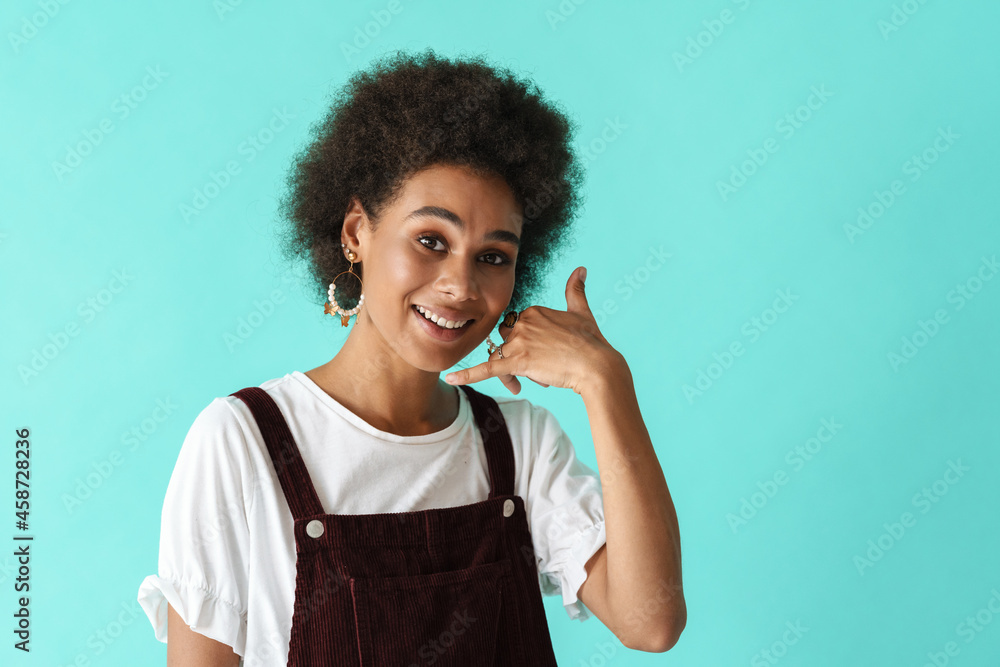 Black young woman in earrings showing handset gesture on camera
