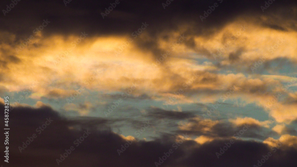 Coucher de soleil, dont les reflets se répercutent sous la base de nuages déchiquetés, à basse altitude
