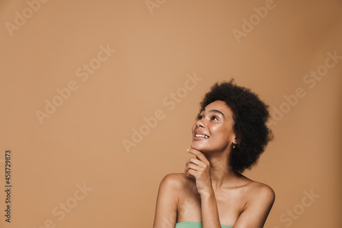 Black brunette curly woman smiling and looking upward