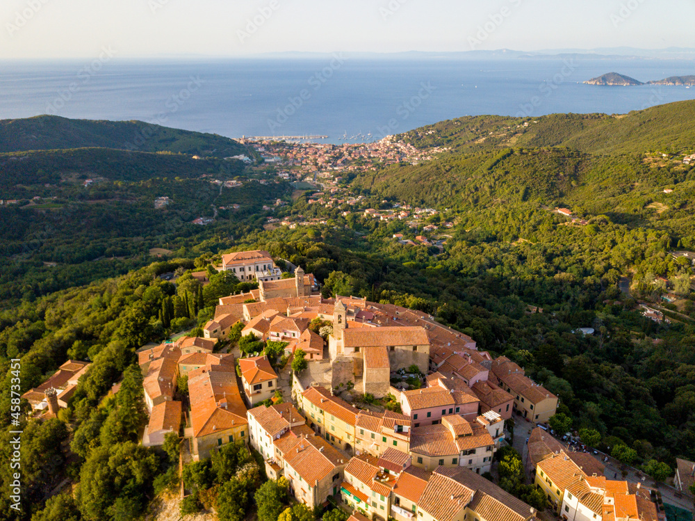 Aerial Drone Panorama of mountain old town Marciana on the islands of Elba Italy with green trees and the mediterranean sea ocean in the background
