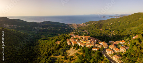 Aerial Drone Panorama of mountain old town Marciana on the islands of Elba Italy with green trees and the mediterranean sea ocean in the background