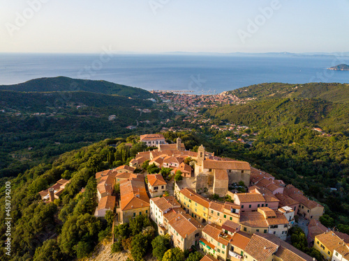 Aerial Drone Panorama of mountain old town Marciana on the islands of Elba Italy with green trees and the mediterranean sea ocean in the background © Tobias