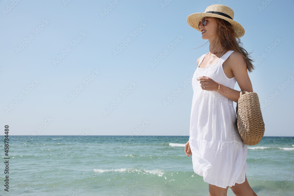 Beautiful woman with beach bag and straw hat near sea Beautiful woman with beach bag and straw hat near sea