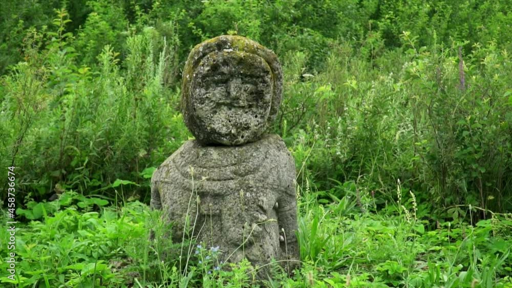 An ancient statue of a stone woman in dense thickets of steppe grass in the rain. An ancient statue of a stone woman in dense thickets of steppe grass in the rain.