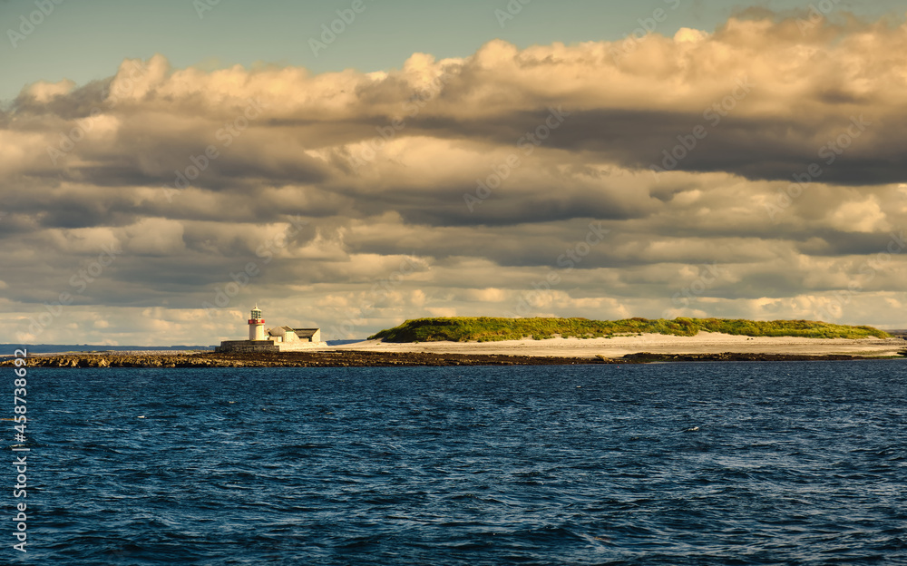 Beautiful seascape scenery with lighthouse under dramatic cloudy skies at Aran islands in West of Ireland 