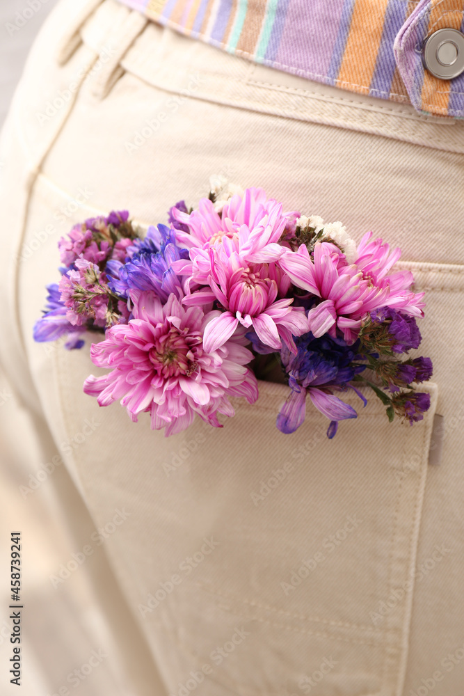 Woman wearing jeans with flowers in pocket, closeup