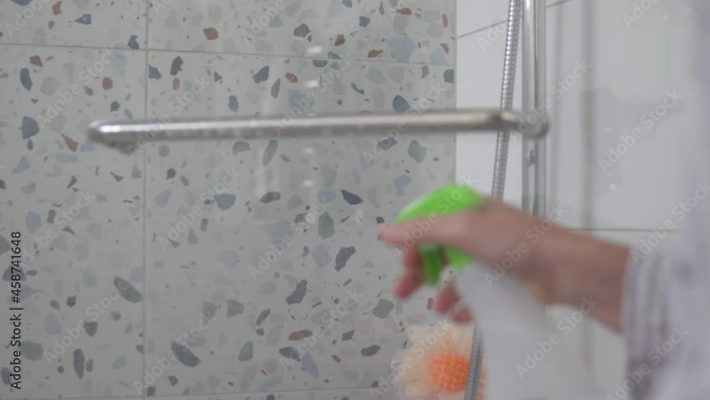 A woman washes a chrome handle on a protective glass in the bathroom with a cleaning agent and a rag. Cleaning chrome-plated bathrooms, bidets A woman washes a chrome handle on a protective glass in the bathroom with a cleaning agent and a rag. Cleaning chrome-plated bathrooms, bidets
