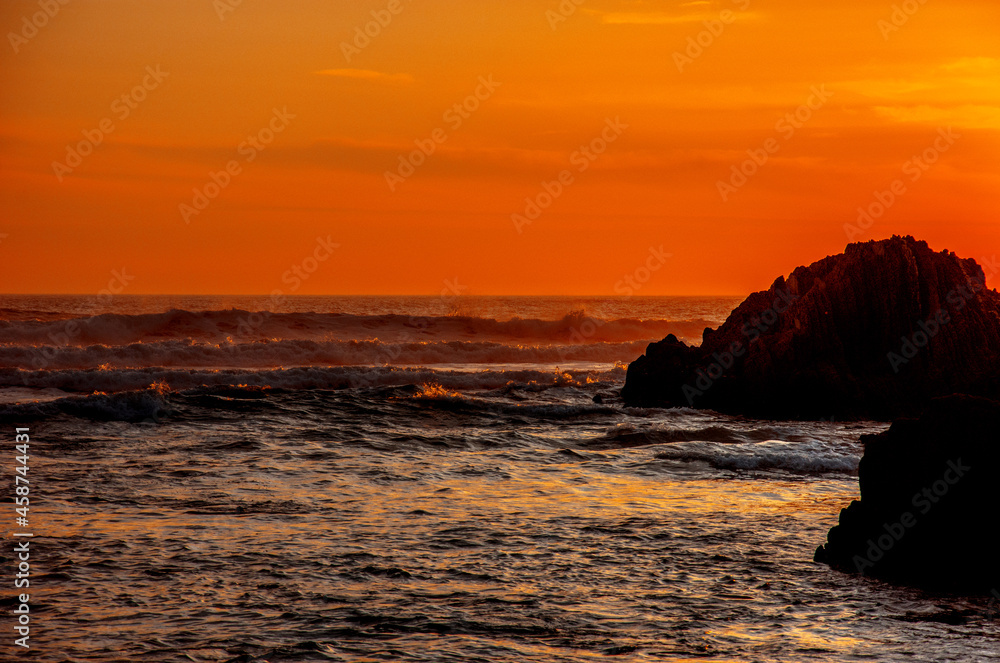 Sunset over the sea at rocky coastline