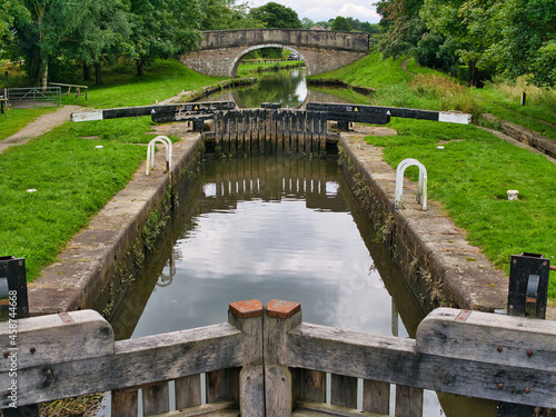 Runnel Brow Lock (No 3) and in the background Runnel Brow Bridge on the Rufford Branch of the Leeds Liverpool Canal. Taken on an overcast day in summer with reflections in the calm water. photo