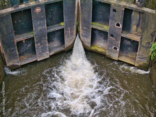 Gushing water leaking from wooden canal lock gates on the Leeds Liverpool Canal in Lancashire, England, UK.