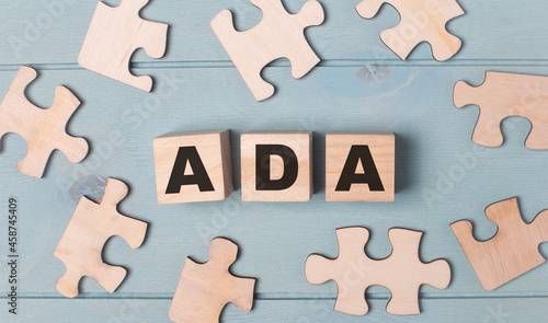 Blank puzzles and wooden cubes with the text ADA Americans with Disabilities Act lie on a light blue background.