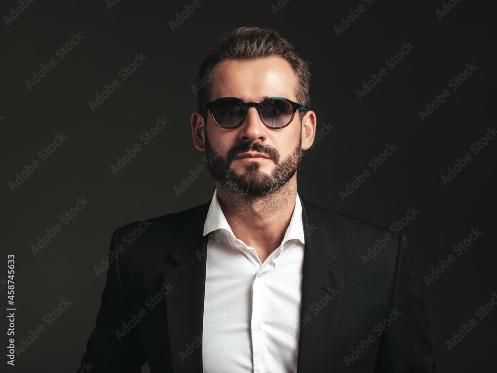 Closeup portrait of handsome confident stylish hipster lambersexual model. Sexy modern man dressed in elegant black suit. Fashion male posing in studio on dark background. In sunglasses Closeup portrait of handsome confident stylish hipster lambersexual model. Sexy modern man dressed in elegant black suit. Fashion male posing in studio on dark background. In sunglasses