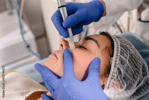 Cosmetologist doing microdermabrasion procedure for woman to refresh her skin tone