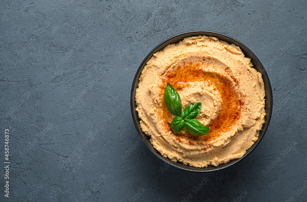 Traditional hummus with paprika and olive oil on a dark background. Top view, copy space. Traditional hummus with paprika and olive oil on a dark background. Top view, copy space.