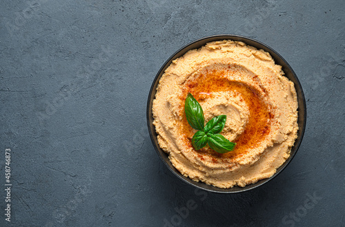 Traditional hummus with paprika and olive oil on a dark background. Top view, copy space.