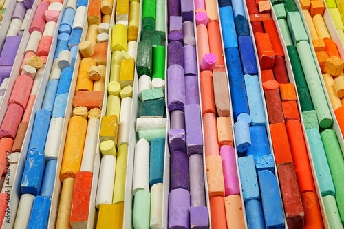 Multi-colored crayons for drawing are stacked in rows by color  background