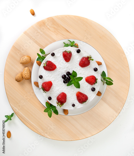 White cake with coconut, almond milk and nuts, garnished with fresh strawberries and mint. Healthy, low-calorie and low-carb dessert. Healthy eating, nutrition and diet. Top view, flat lay
