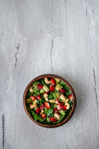 Healthy veggie salad with avocado, arugula, spinach, strawberries, cashews and seeds- low carbohydrate, low calorie diet. Healthy eating, nutrition and diet concept. Close-up, selective focus