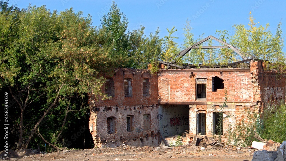 An abandoned historical building built in the 19th century. An old ruined building built of red brick. Trees grow on the ruins of an old house.