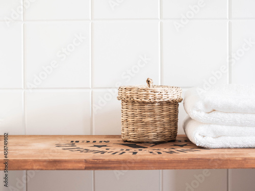 Bath background front view with straw box and white towels on brown wood shelf and wall tiles