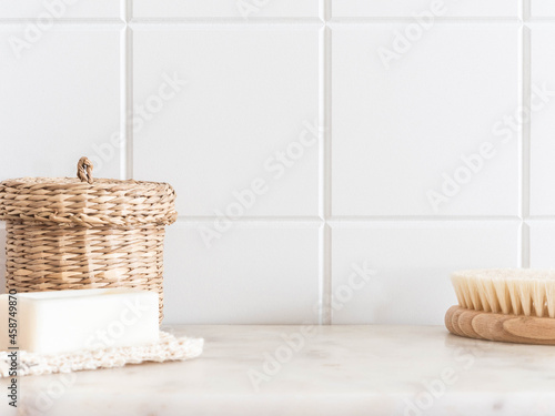 Bath background front view with straw box, wood brush for body and white soap on white marble shelf