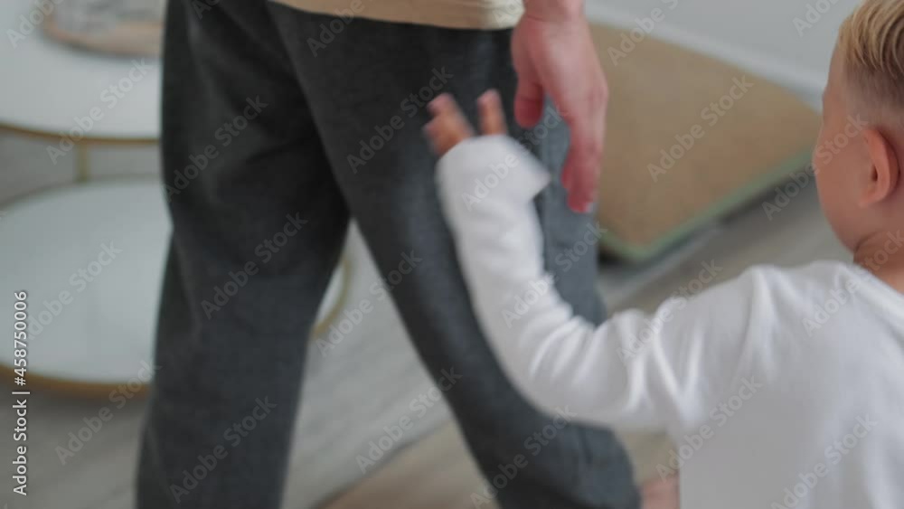 Cropped view of a father spending time with his little son while walking and holding his hand at home Cropped view of a father spending time with his little son while walking and holding his hand at home