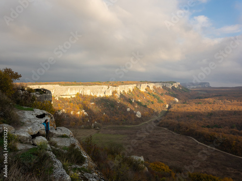 The girl looks into the distance at the mountains. Beautiful views of mountain on a sunny autumn day. The cave city of Eski-Kermen in the Bakhchysarai district, Crimea