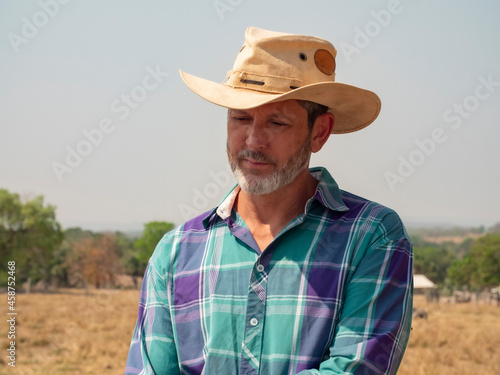 Cowboy is riding his horse on a cattle farm with very dry land