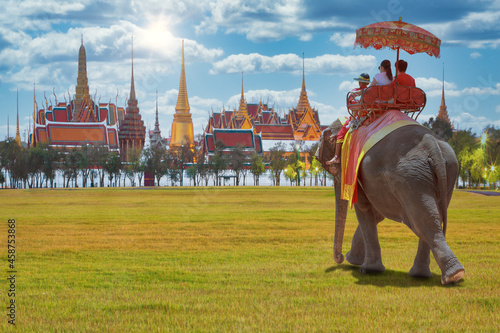 Couple tourists on an elephant ride tour of the grand architecture, a venue now mostly used for ceremonial events. The Buddhist temple of Wat Phra Kaew at the Grand Palace in Bangkok, Thailand