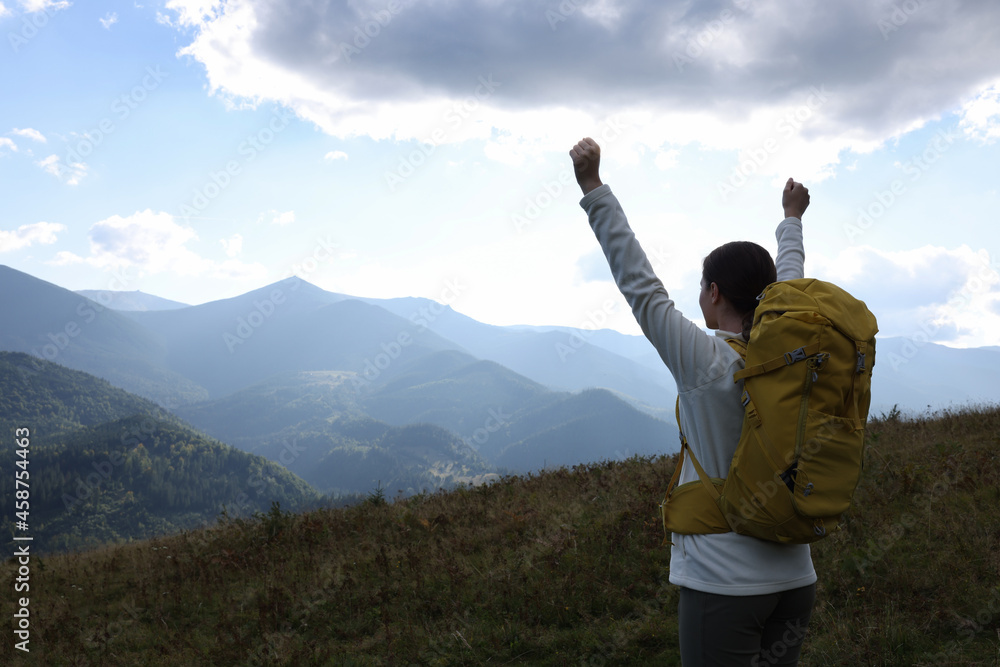 Triumphant tourist on top of mountain, back view. Space for text