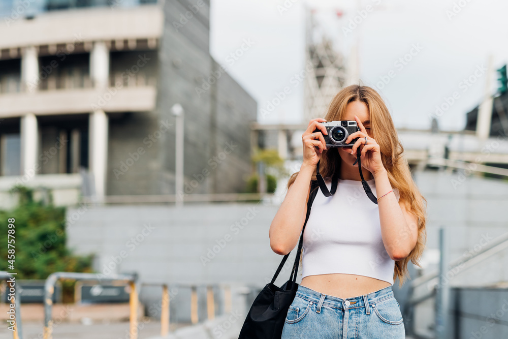 Young caucasian woman freelance photographer taking photos outdoors searching inspiration