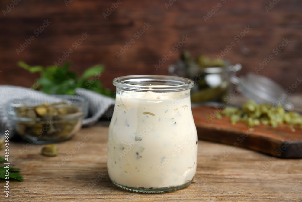 Tasty tartar sauce in glass jar on wooden table Tasty tartar sauce in glass jar on wooden table