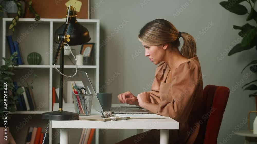 Woman speaking on smartphone and writing notes, working remotely from home office. Businesswoman using laptop, typing on keyboard. Executive female manager sitting and doing officework. Woman speaking on smartphone and writing notes, working remotely from home office. Businesswoman using laptop, typing on keyboard. Executive female manager sitting and doing officework.