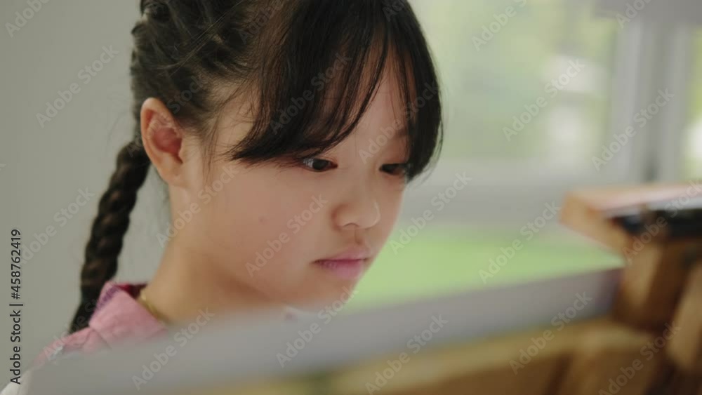 A close-up view of a thinking asian girl study drawing on easel in the modern art school A close-up view of a thinking asian girl study drawing on easel in the modern art school
