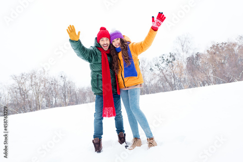 Full body photo of young couple happy positive smile hug cuddle wave hand hello hi travel snowy weather outdoors