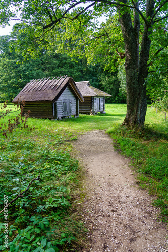 Small wooden houses in the forest with a dirt driveway.