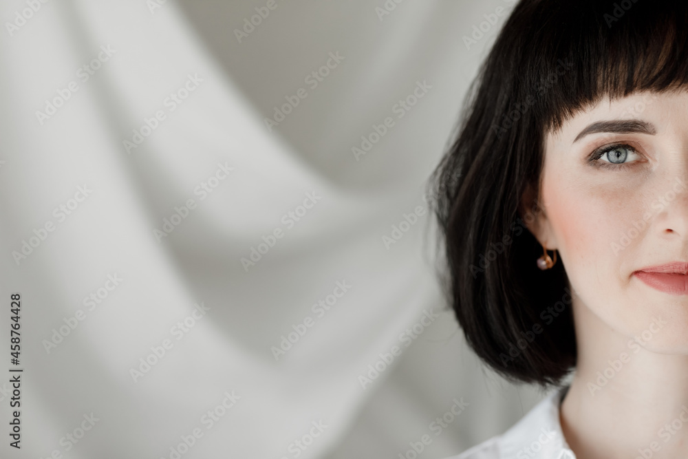 portrait of beautiful brunette young woman with short hair is looking at the camera against the background of a wall with white cloth. copy space. portrait of beautiful brunette young woman with short hair is looking at the camera against the background of a wall with white cloth. copy space.