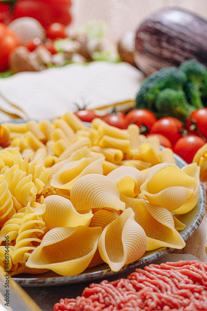 different types of italian pasta on a wooden background with various ingredients for cooking traditional italian dishes