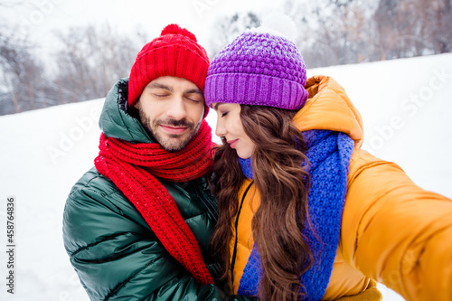 Photo of young lovely married couple enjoy time together hug cuddle make selfie travel winter snowy park